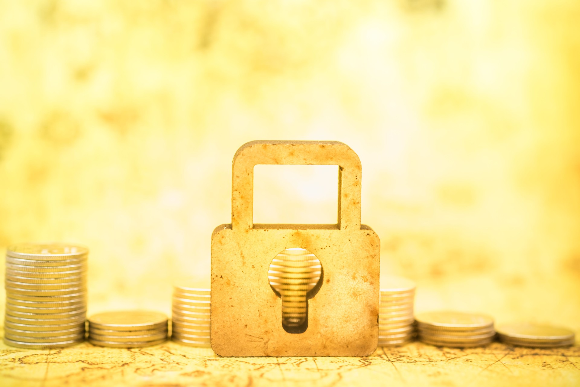 Money and Security Concept. Wooden master key lock symbol in front of stack of coins with world map as background.